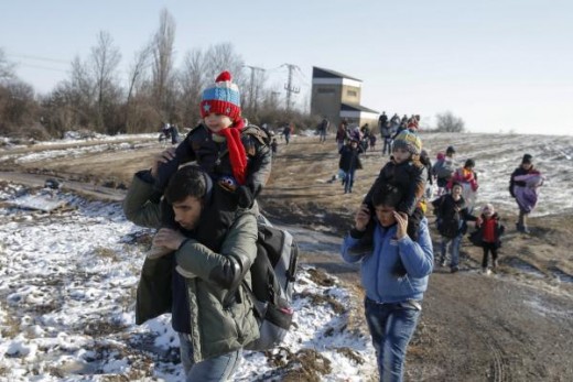 Migrants carry children as they walk through a field after crossing the border from Macedonia, near the village of Miratovac, Serbia